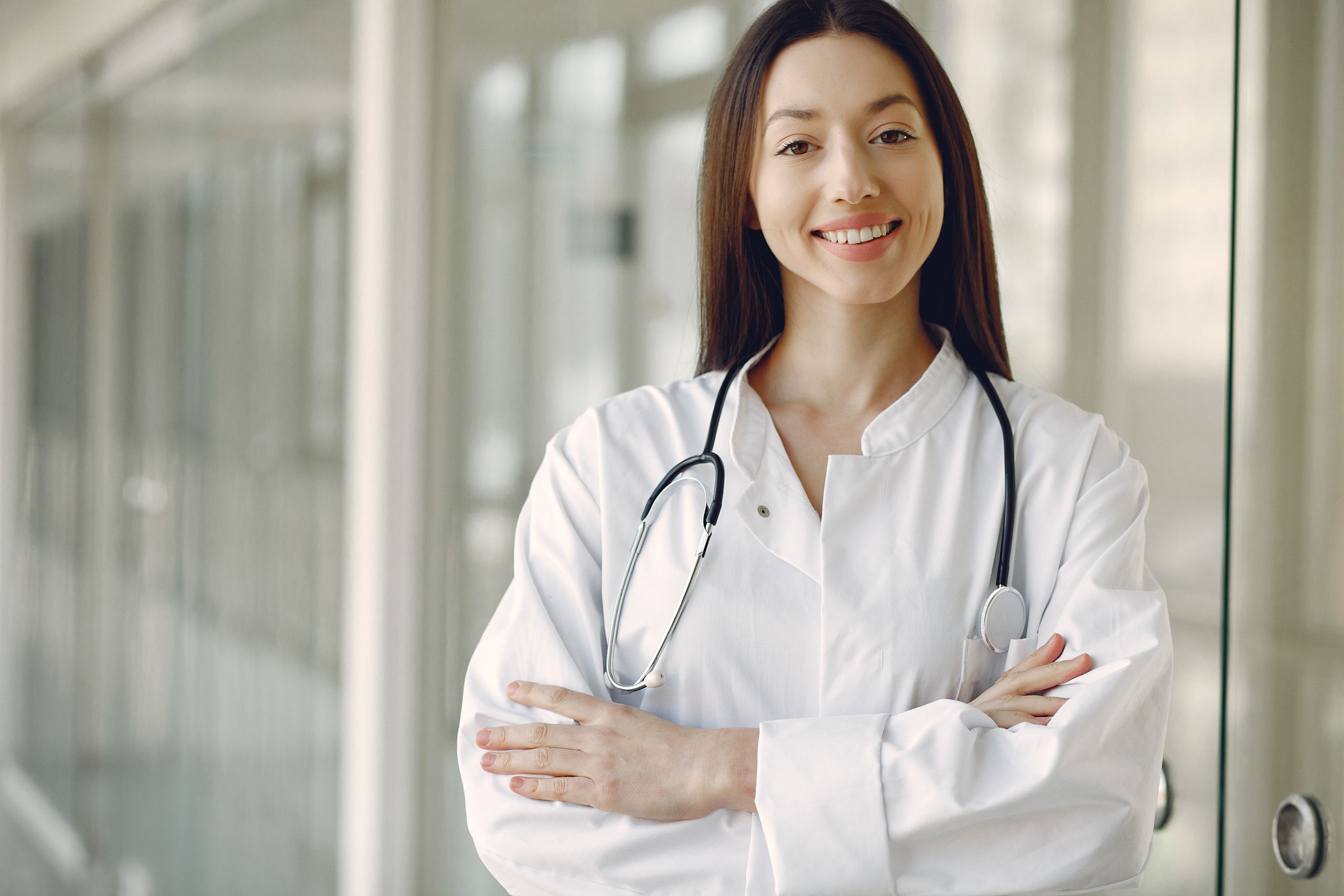 Crop doctor in medical uniform with stethoscope standing in clinic corridor